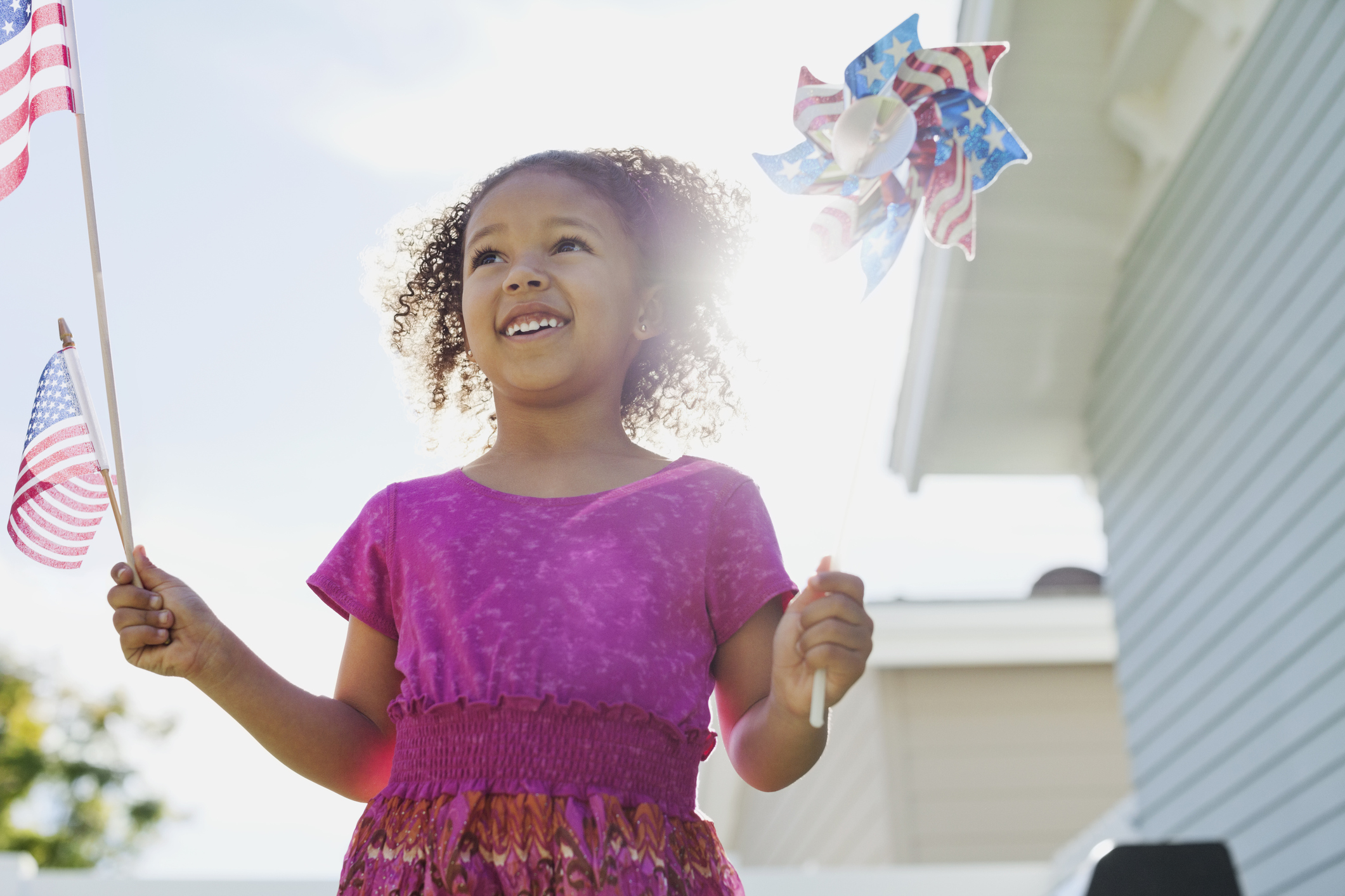 Happy girl holding American flag and pinwheel on 4th of July