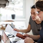 Couple discussing nanny taxes while using laptop at table