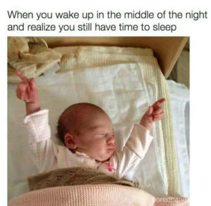 A picture of a baby laying under the covers with it's arms in the air like it is celebrating. The caption reads: "When you wake up in the middle of the night and realize you still have time to sleep."