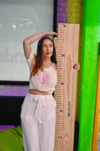 Daniella Cassoni poses by life size ruler to measure how tall she is.