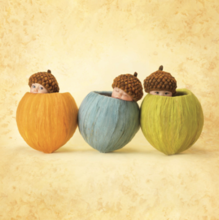 anne geddes photo of babies with acorn hats inside of yarn covered acorns