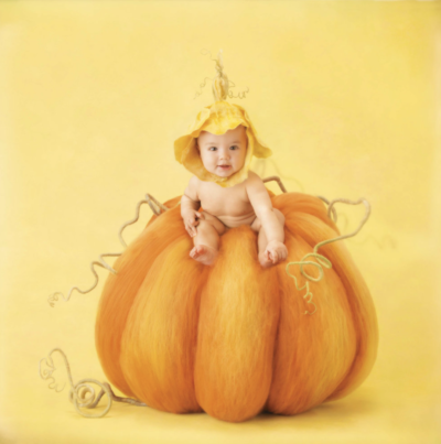 anne geddes photo of a baby sitting on top of a pumpkin