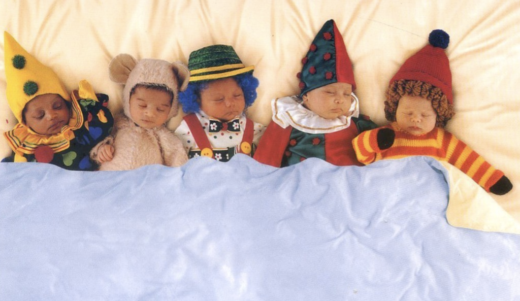 anne geddes photo of babies napping in a bed while dressed up as clowns