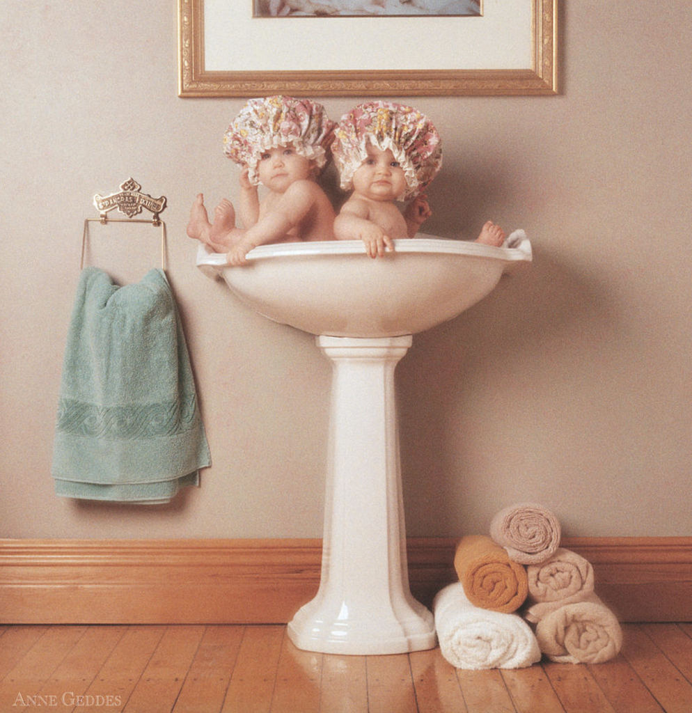anne geddes photo of two babies in a bathroom sink with shower caps on