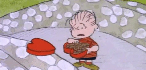 the peanuts character linus is upset and throwing chocolates out of a heart-shaped box