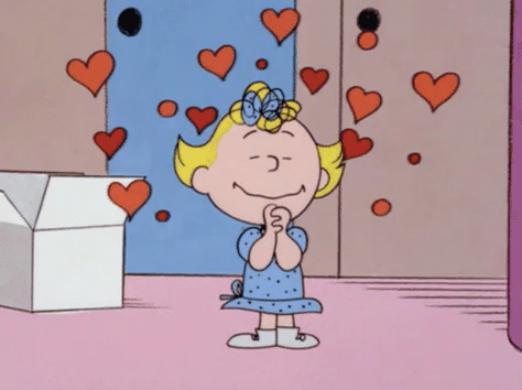 Sally from the Peanuts cartoon is very happy with lots of hearts around her