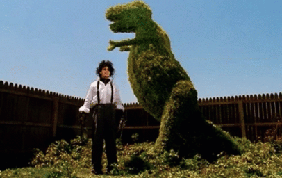 edward scissorhands trims a bush to look like a dinosaur