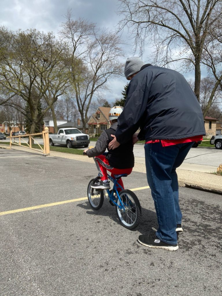 a father helps his son ride a bike