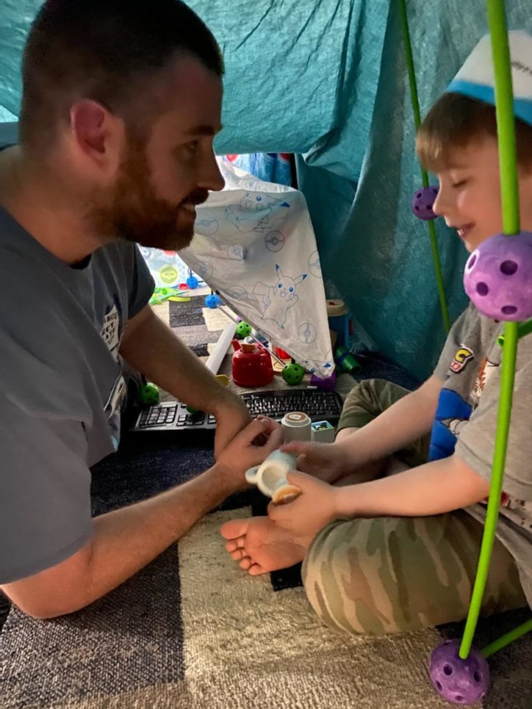 a father and son play inside of an indoor fort