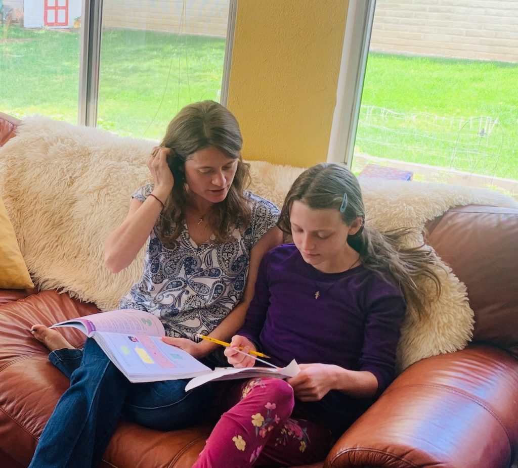 a mom helps her daughter with schoolwork at home