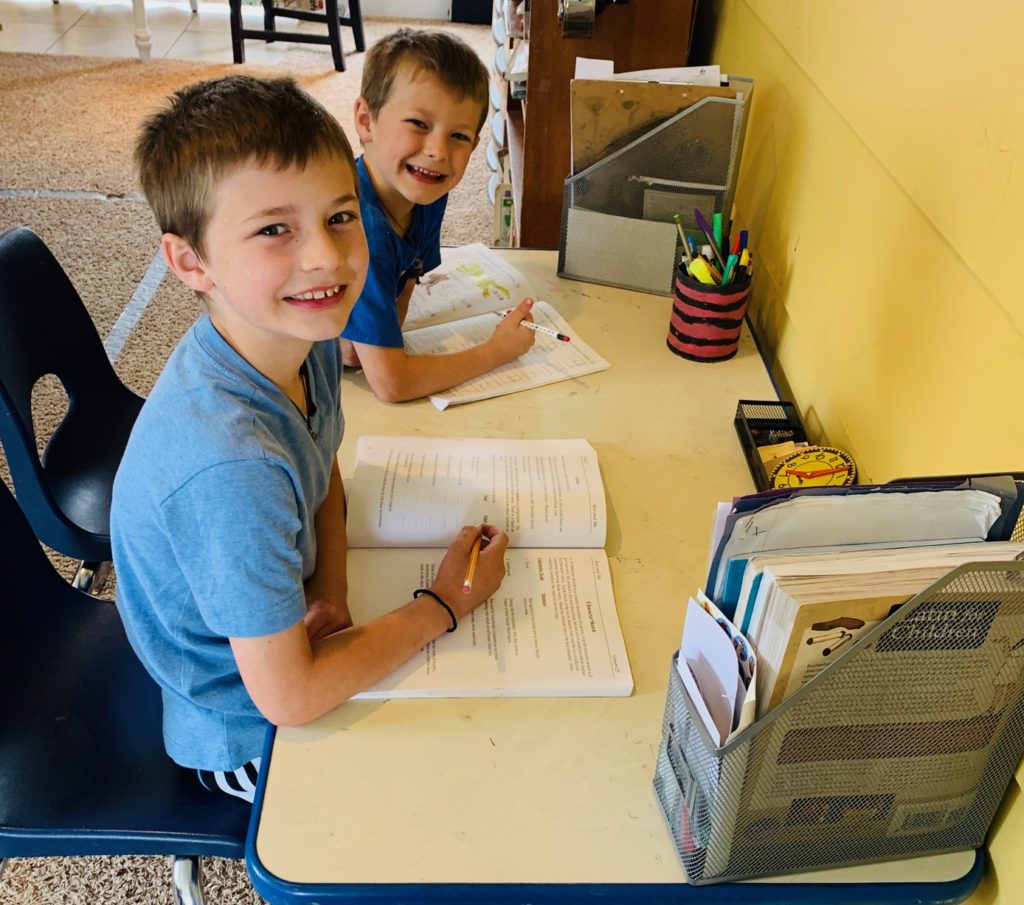 two boys work on schoolwork at home