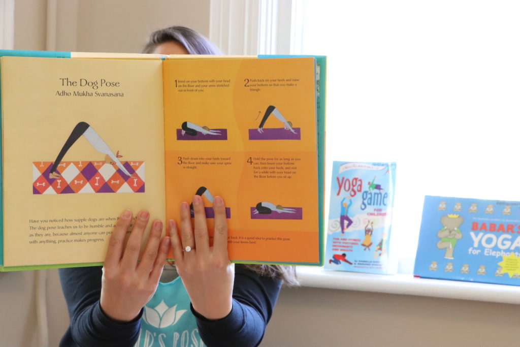 a woman shows a book of yoga poses made for kids