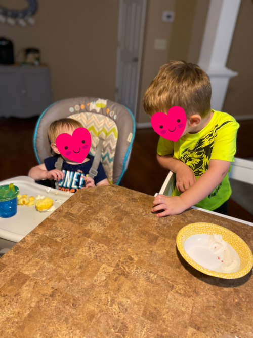 two young brothers laugh at the breakfast table together