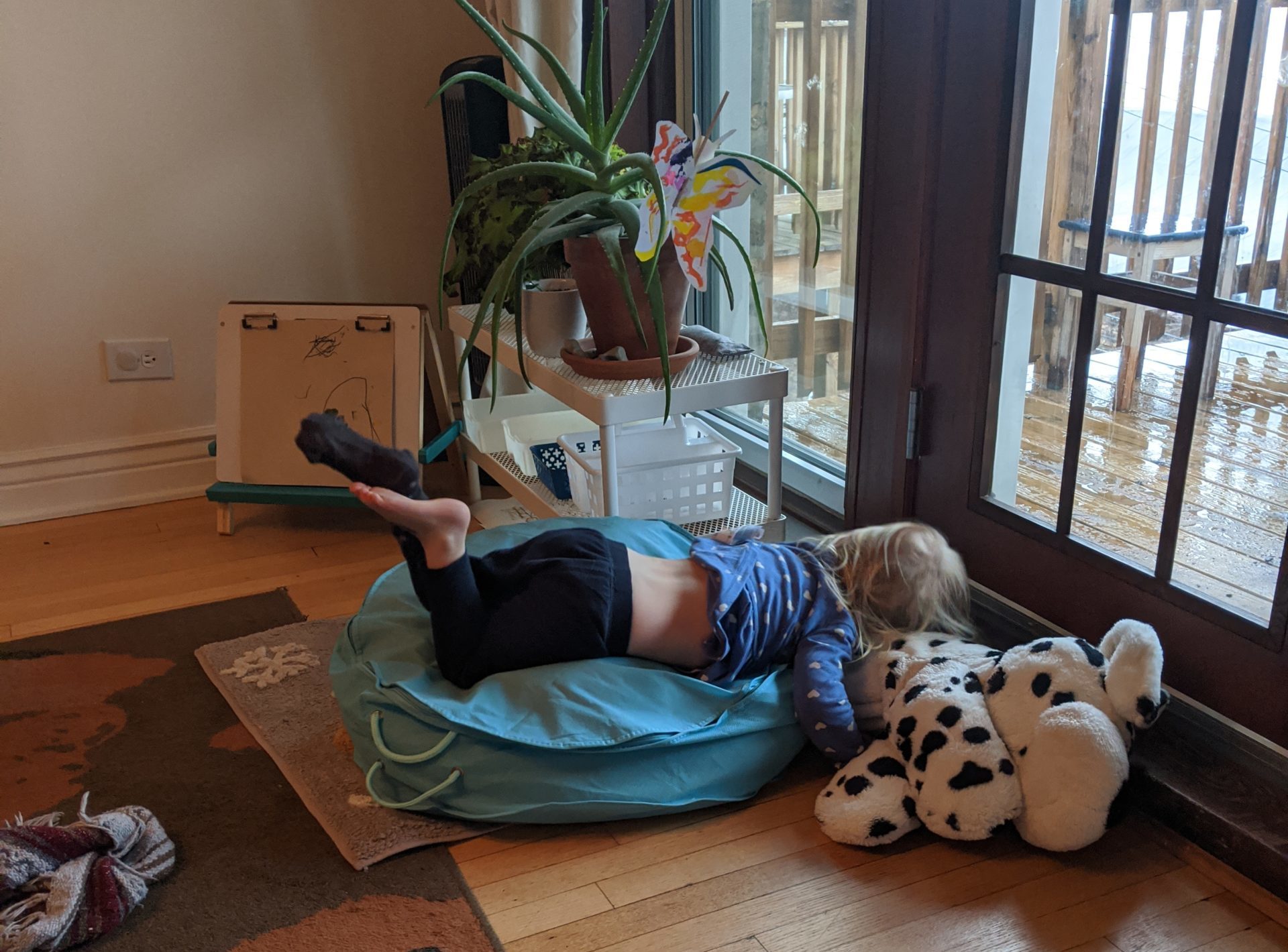 an upset toddler is face-down on a bean bag with only one sock on