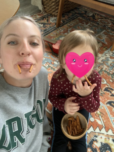 a nanny and her child make silly faces with pretzels in their mouths