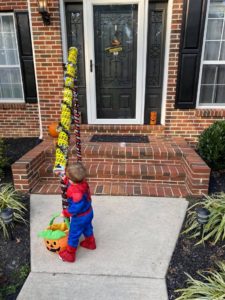 a boy in a halloween costume gets candy from a chute in front of a house