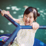 little girl playing on the merry go round in the playground joyfully