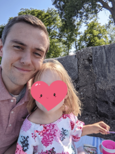 A father poses for a picture with his daughter outside.