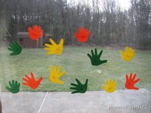 colorful paper cutouts in the shape of hands on a window