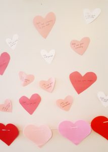 Heart-shaped paper cutouts on the wall with Valentine's messages