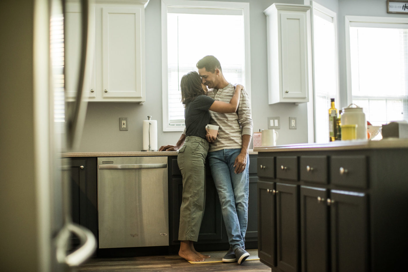 Husband and wife hugging and talking in kitchen
