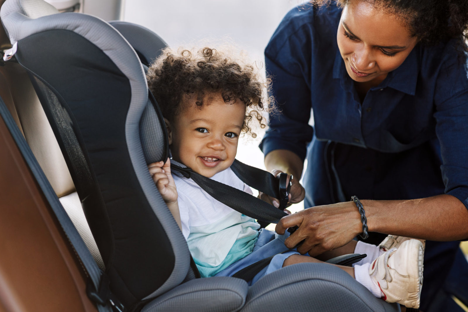 nanny buckles child into car seat