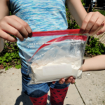 A girl holds a plastic bag with ice cream ingredients inside.