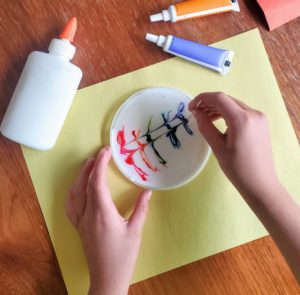 A child swirls food coloring with a toothpick.